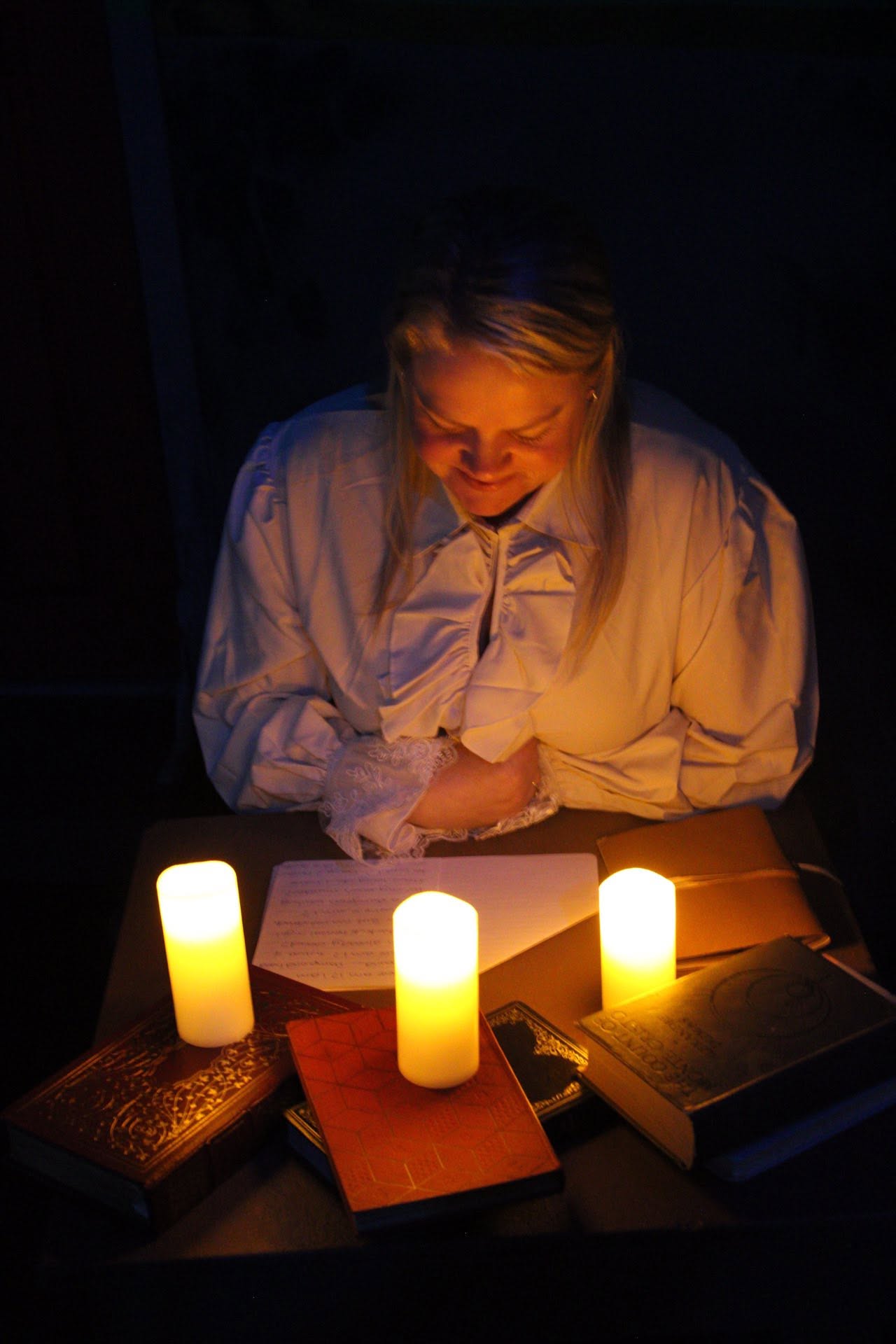 An actor reads by candlelight in a Boilerhouse Theatre production