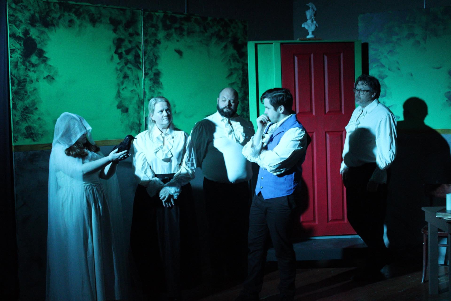 The ensemble gathered before a red door