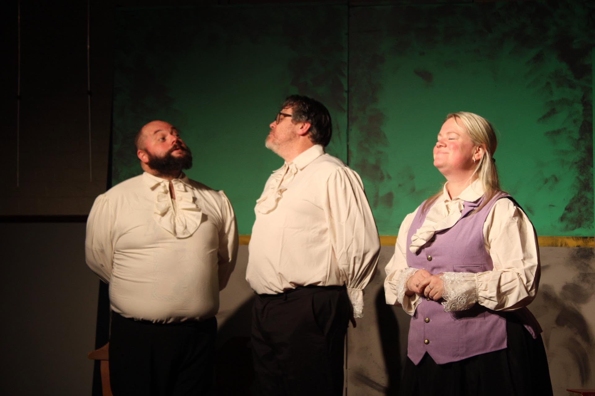 Three performers in period dress, faces raised
